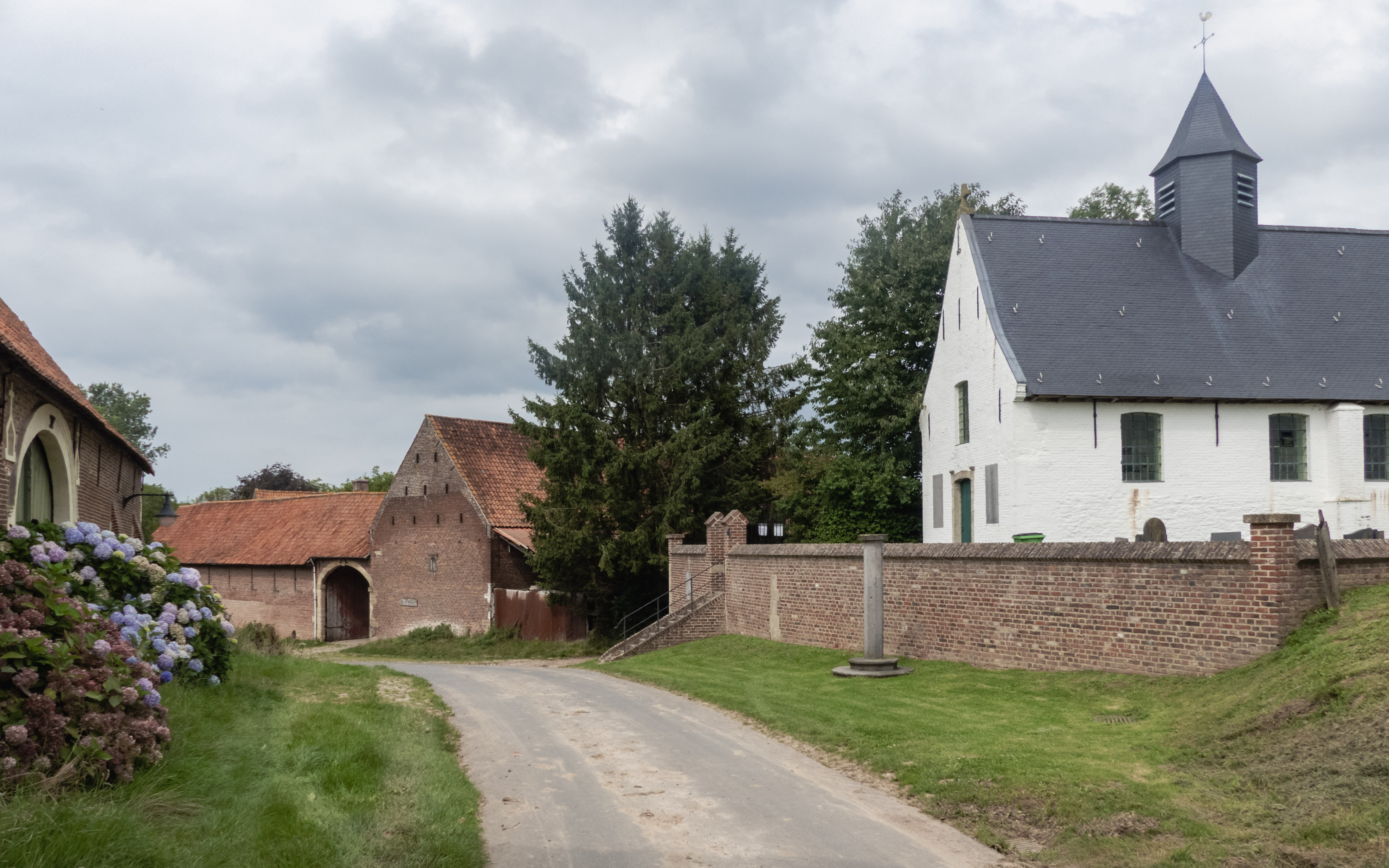 Een mooie weg door een dorpje, met een kerk en een baksten boerderij
