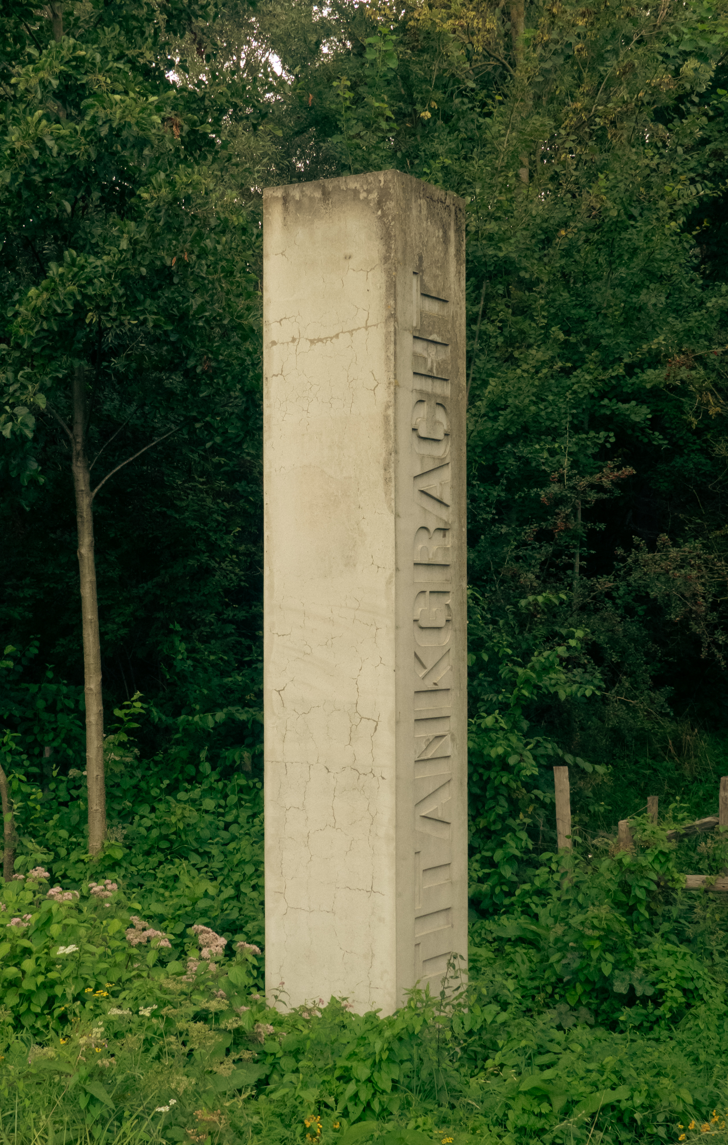 Een betonnen paal in de natuur waar antitankgracht op staat